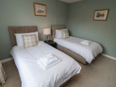 A bedroom with two single beds with white bedding and folded towels on top at Sparrow House in Alnwick