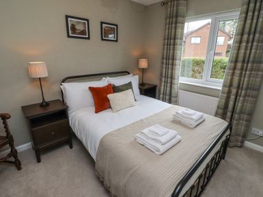 A bedroom with a bed with towels on it two bedside tables with lamps and a window with curtains at Sparrow House in Alnwick