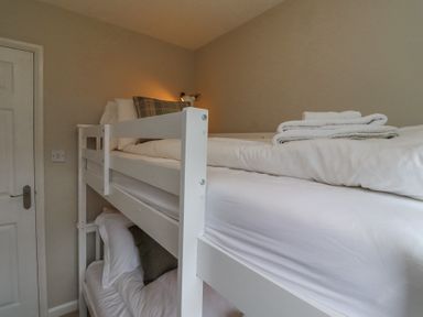 A bedroom with a white bunk bed and folded towels on the top bunk at Sparrow House in Alnwick