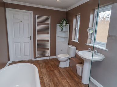 A bathroom with a bathtub toilet sink wall cabinet and towel radiator at Sparrow House in Alnwick