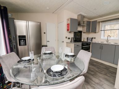 A kitchen with a glass dining table set for four and grey cabinets at The Hideout in Gilfachrheda near Llanarth