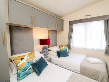 A bedroom with two single beds a lamp between the beds and storage cabinets above at The Hideout in Gilfachrheda near Llanarth