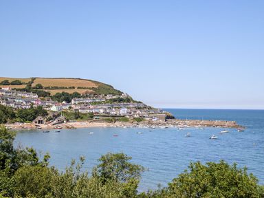 A coastal village with houses on a hillside overlooking a bay with boats at The Hideout in Gilfachrheda near Llanarth