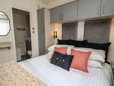 A bedroom with a bed with pillows and an open door to a bathroom at The Hideout in Gilfachrheda near Llanarth