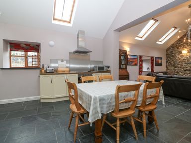 A kitchen and dining area with a table and chairs and a living room with skylights at The Old Dairy in Sarn Bach near Abersoch
