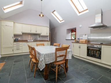 A kitchen with a table and six chairs under skylights at The Old Dairy in Sarn Bach near Abersoch