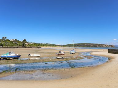 A beach with several boats resting on the sand during low tide at The Old Dairy in Sarn Bach near Abersoch