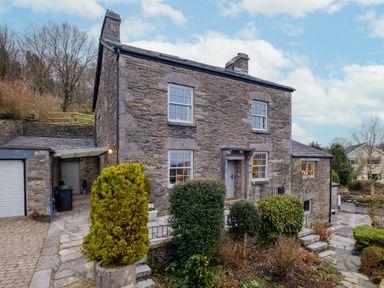A stone house with four windows a front door and shrubs in front at Sunny Brae in Lindale