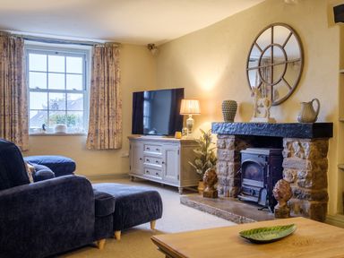 A living room with a stone fireplace a round mirror a television and a blue sofa at Sunny Brae in Lindale