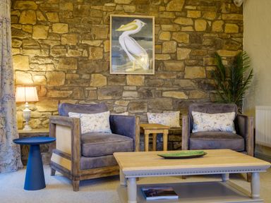 A sitting area with two armchairs a coffee table a side table a lamp a framed pelican picture and a potted plant at Sunny Brae in Lindale