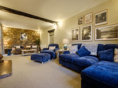 A living room with blue sofas armchairs a stone wall and framed pictures at Sunny Brae in Lindale