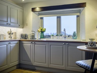 A kitchen with cabinets countertop toaster kettle flowers and plants by the window at Sunny Brae in Lindale