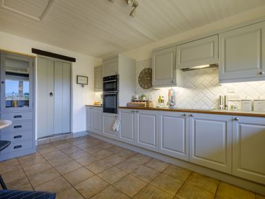 A kitchen with gray cabinets wooden countertop double oven and tiled floor at Sunny Brae in Lindale