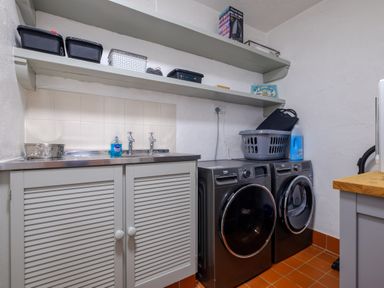 A laundry room with washing machine and dryer cabinets shelves and cleaning supplies at Sunny Brae in Lindale