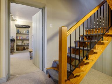 A staircase with carpeted steps and black railings next to a doorway leading into a room with shelves and a bench at Sunny Brae in Lindale