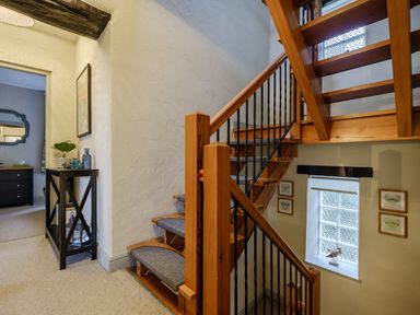A wooden staircase with carpeted steps leading to a hallway with a black console table and a doorway at Sunny Brae in Lindale