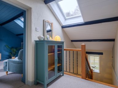 A hallway with a teal cabinet under a skylight and a staircase with wooden railing at Sunny Brae in Lindale