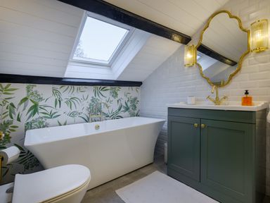 A bathroom with a bathtub under a skylight and a green vanity with a gold mirror at Sunny Brae in Lindale