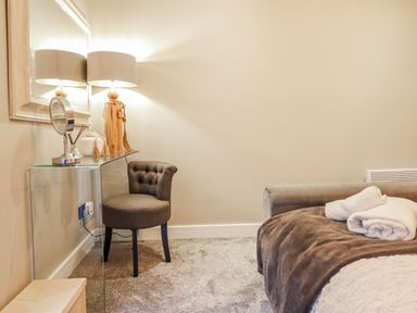 A bedroom with a chair and mirror at Hafod Y Bryn in Harlech
