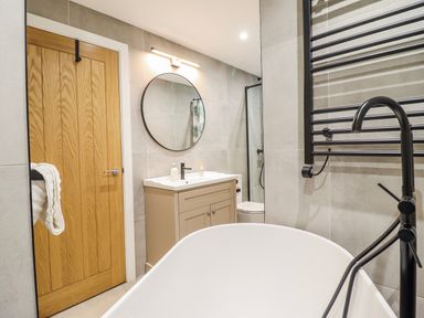 A bathroom with a bathtub, sink, and mirror at Hafod Y Bryn in Harlech