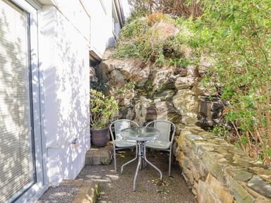 An outdoor area with a table and chairs next to a rock wall at Hafod Y Bryn Harlech