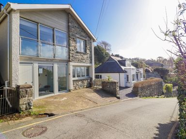 An exterior view of a house with windows and a stone wall at Hafod Y Bryn in Harlech