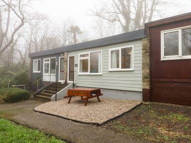 A house with stairs leading to the entrance and a wooden bench on gravel outside at 2 The Glade in Kilkhampton
