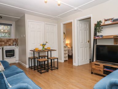 A living room with a wooden dining table set and blue sofas at 2 The Glade in Kilkhampton