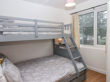 A bedroom with a bunk bed near a window and a lamp at 2 The Glade in Kilkhampton