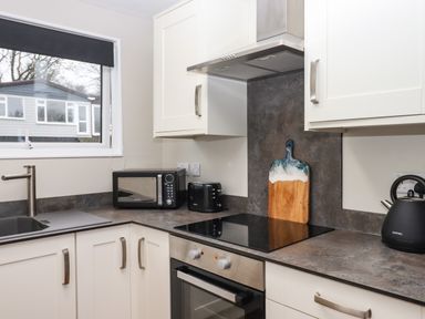A kitchen with white cabinets and a window above a sink at 15 The Park in Kilkhampton
