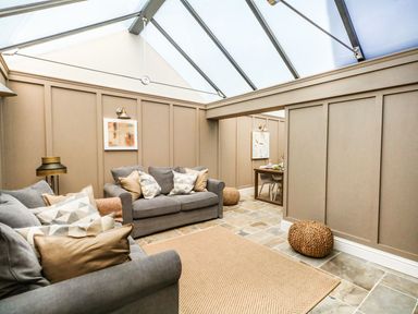 A living room with two grey sofas and a woven rug under a glass ceiling at The Apple Loft at Jordan House in Preston