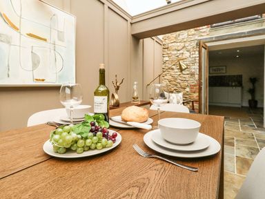 A dining table set with plates bowls wine glasses grapes bread and a wine bottle in a room with stone walls at The Apple Loft at Jordan House in Preston