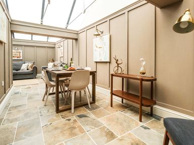 A dining area with a wooden table and chairs next to a side table with decor and a sofa in the background at The Apple Loft at Jordan House in Preston