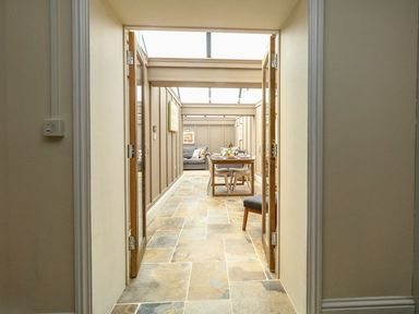 A hallway leading to a dining area with a table and chairs and a seating area with a sofa at The Apple Loft at Jordan House in Preston
