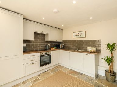 A kitchen with white cabinets a built-in oven a sink and a potted plant at The Apple Loft at Jordan House in Preston