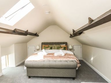 A bedroom with a double bed and skylight under a slanted ceiling with exposed beams at The Apple Loft at Jordan House in Preston
