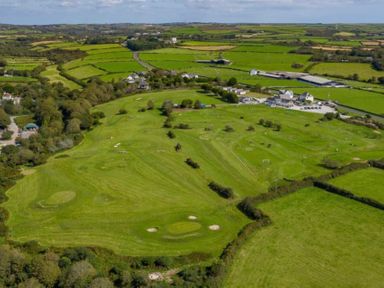 An aerial view of a golf course with surrounding fields and buildings at Wheal Amelia Lodge in Wendron near Helston
