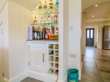 A built-in bar cabinet with bottles of liquor and wine in a hallway at Channel View House in Wadebridge