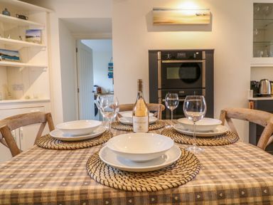 A dining table set with plates and glasses in a kitchen at Channel View House in Wadebridge
