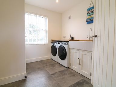 A laundry room with washing machine dryer sink and window at Channel View House in Wadebridge