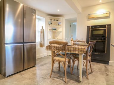 A kitchen with a stainless steel refrigerator a dining table with four chairs and built in ovens at Channel View House in Wadebridge