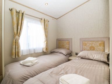 A bedroom with two single beds and towels on each bed at Snape Lodge in Towyn