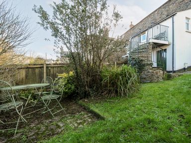 A garden with metal chairs and table near a stone staircase outside a house at Lowen Cottage in Boscastle