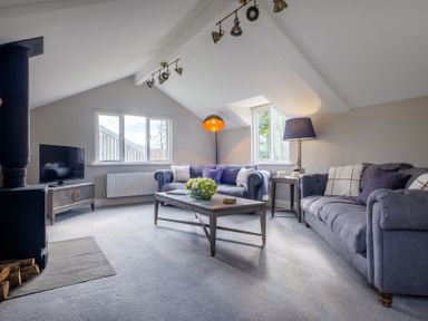 A living room with two sofas a coffee table a television and a wood stove at Gate House in Killington near Sedbergh