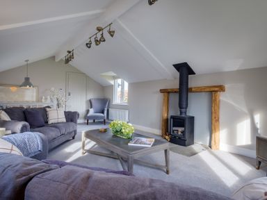A living room with sofas a coffee table a wood burning stove and an armchair at Gate House in Killington near Sedbergh