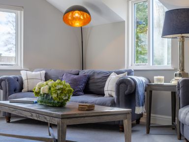 A living room with a gray sofa a wooden coffee table with flowers and cushions at Gate House Killington near Sedbergh