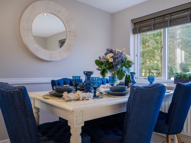 A dining room with a white table set with blue glasses and blue chairs at Gate House in Killington near Sedbergh