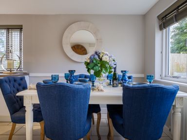 A dining room with a white table set with blue glasses and blue chairs at Gate House in Killington near Sedbergh