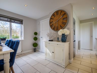 A dining area with blue chairs a white sideboard with decor and a large wall clock at Gate House in Killington near Sedbergh