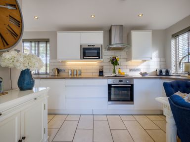 A kitchen with white cabinets a built in oven microwave and a vase of flowers on the counter at Gate House in Killington near Sedbergh